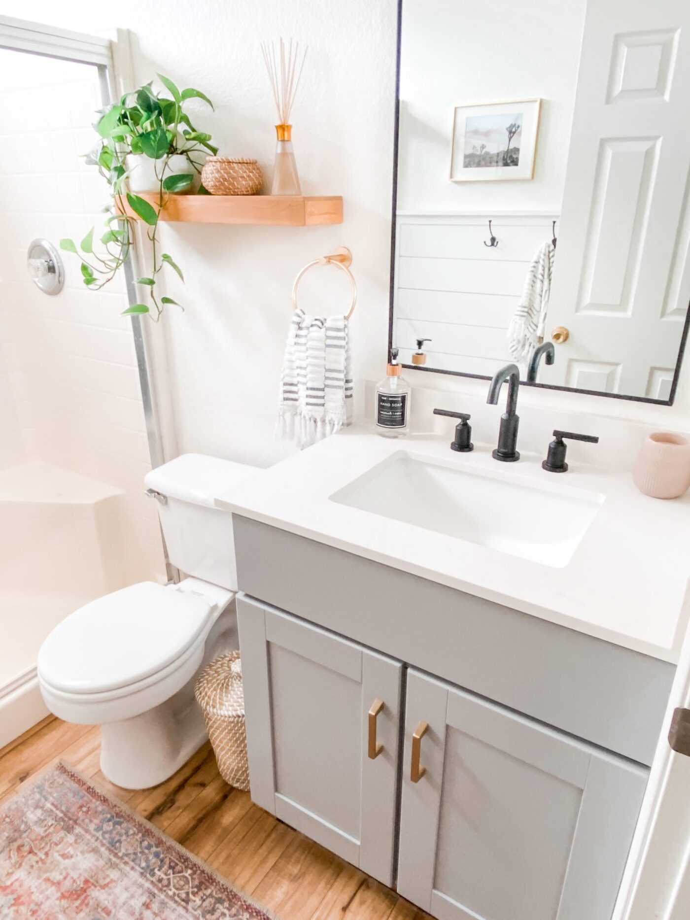 Completed bathroom remodel with grey vanity, quartz top and black fixtures