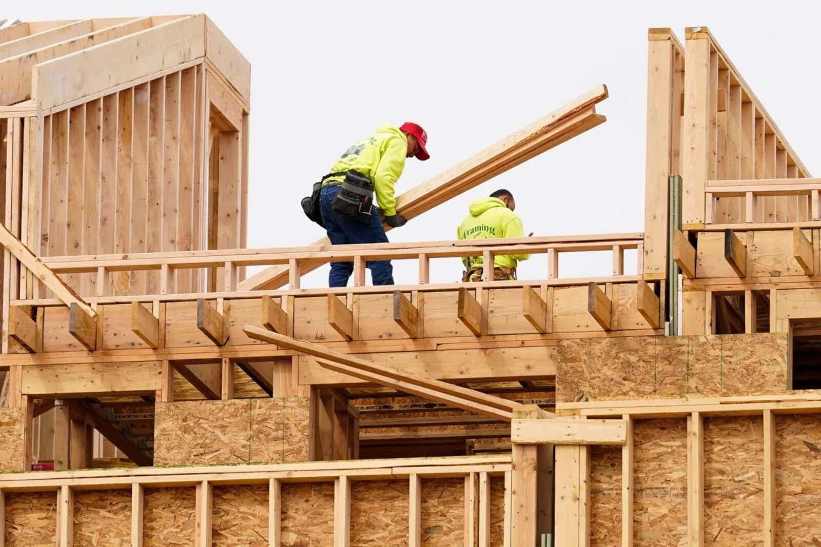 Framing crew installing roof rafters on a two-story home